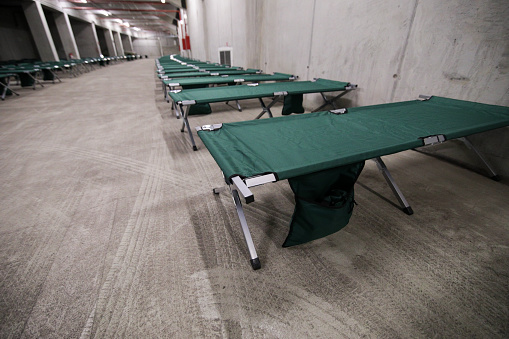Camp folding cots are being set up in the underground parking of a stadium and wait for refugees, during the drill of a catastrophic earthquake in the city in which there are many victims