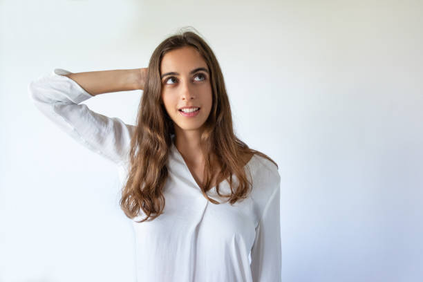 istock Pensive student girl in white blouse scratching back of head 1054963228