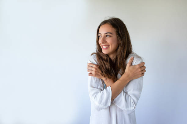 Smiling young woman getting cold and holding her shoulders
