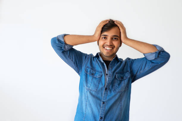 istock Excited Indian man holding head in hand and smiling at camera 1054964424