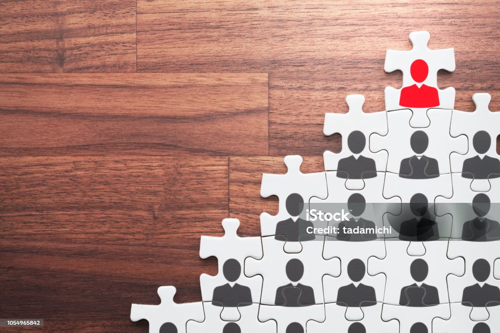 Successful leader and corporate hierarchy. Human resource management and leadership concept.  Assembling jigsaw puzzle on wood desk. Organized Group Stock Photo