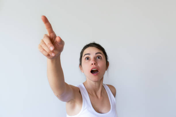 istock Shocked attractive woman pointing at something and looking up 1054966020