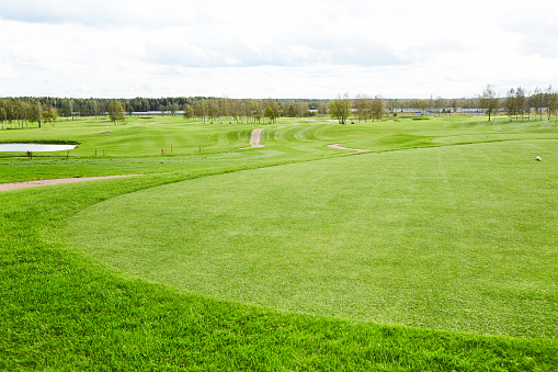 Vast green field for playing outdoor games such as golf and riverside surrounded by trees on background