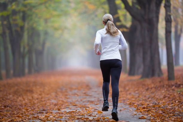 istock rear view woman running alone through park in autumn 1054966762