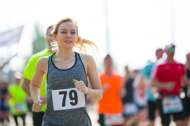 Elderly woman exercising. Fit senior lady running on sunny stadium in summer city. Fitness in retirement age. Active female stretching after healthy workout outdoors. Sport for retired person.