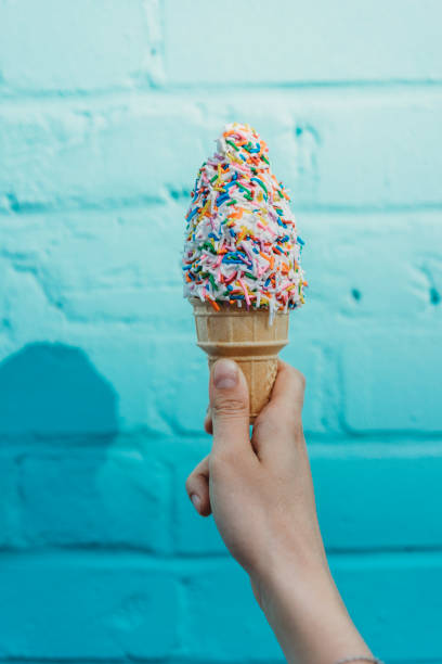 istock Holding a frozen yogurt against blue bricks wall 1054969580