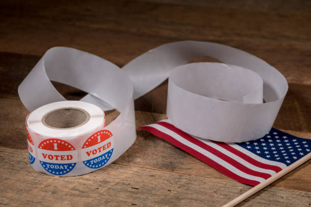 istock Roll of I Voted Today paper stickers on table with US Flag 1054970344