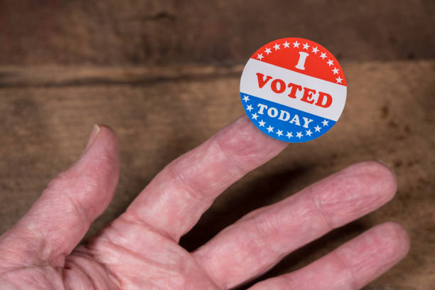istock I Voted Today paper sticker on mans finger on rustic wooden table 1054970364