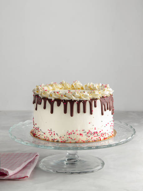 istock Birthday Drip Layered Cake with chocolate ganache and sprinkles on a white background with party decor. Horizontal. Copy space. Celebration concept. Trendy Drip Cake. 1054970872