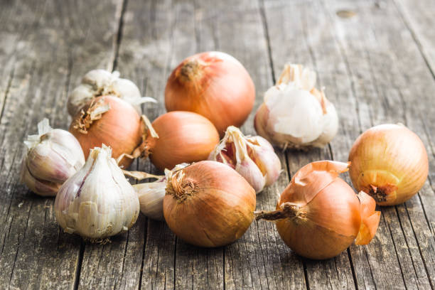 istock Fresh onion and garlic bulbs on old wooden table. 1054971256