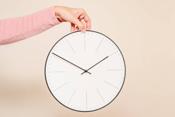 istock Woman hand hold wall clock on a white background 1054976848