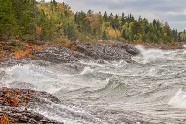 Wild stormy waves on rocky shore of Lake Superior along Autumn forest stock photo