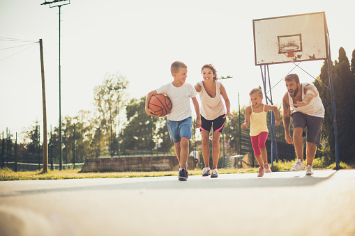 Summer day for play. Family playing basketball.