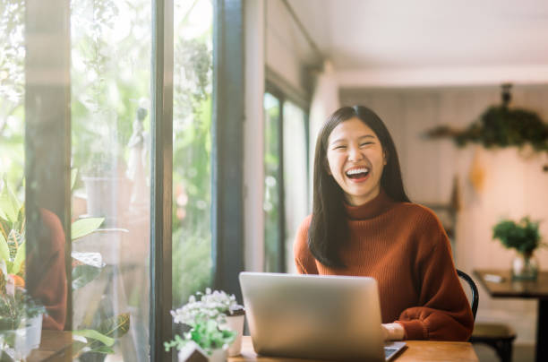 young Asian girl working at a coffee shop with a laptop Happy young asian girl working at a coffee shop with a laptop chinese woman stock pictures, royalty-free photos & images