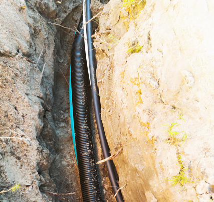 Optical fiber cables being laid in trenches.
