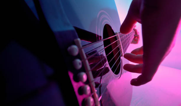 Acoustic guitar played by a girl and colorful lights stock photo