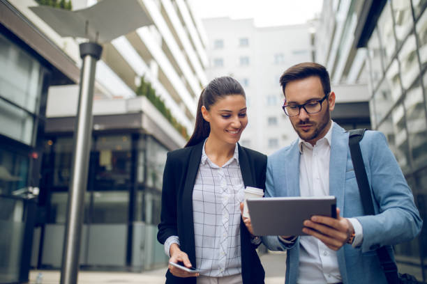 istock Business team discussing business project using tablet computer outdoors 1054995074