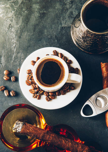 istock Cup of coffee, coffee beans, ashtray with cigar on dark background 1054999212