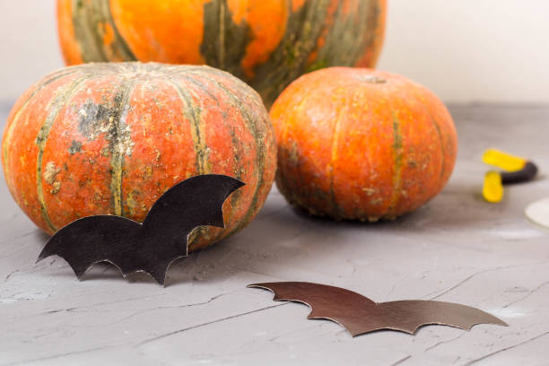 istock orange pumpkin and paper bats on white table, halloween concept 1054999620