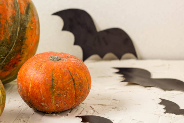 istock orange pumpkin and paper bats on white table, halloween concept 1054999628