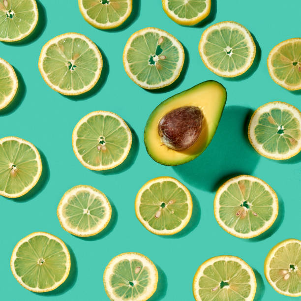 istock Fresh natural organic pattern with lemon fruit and single half of avocado on a pastel green background. Flat lay. 1055002648