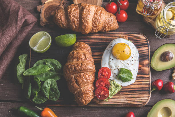 istock croissant with guacamole avocado, fried egg and tomato, spinach leaves. vegetarian dish 1055010480