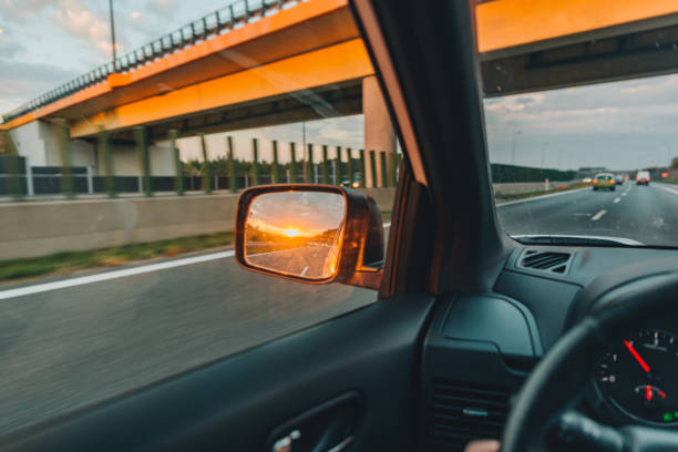 istock first-person point of view. sunset in car mirror 1055016710