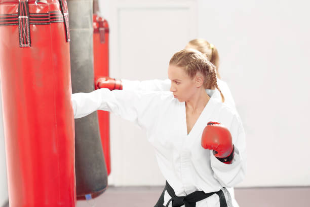 istock Two strong women boxing red heavy bag in gym. 1055020084