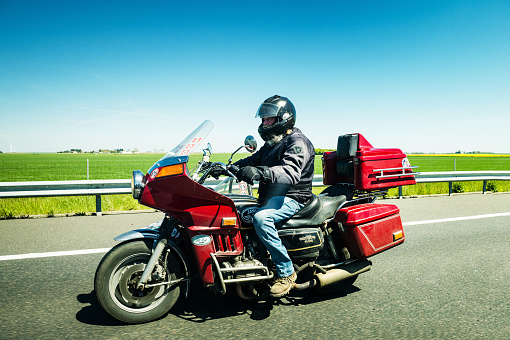 FRANCE - MAY 5, 2016: Motorcyclist driving vintage Honda Goldwing GL1000 motorcycle French highway - holiday travel style vintage lifestyle