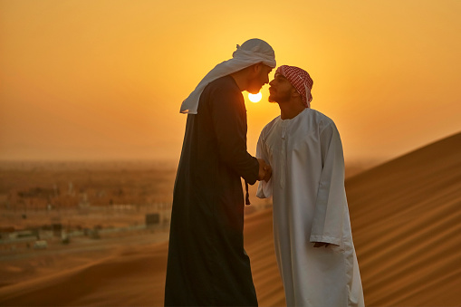 Middle Eastern men greeting in the traditional Arab culture at desert.