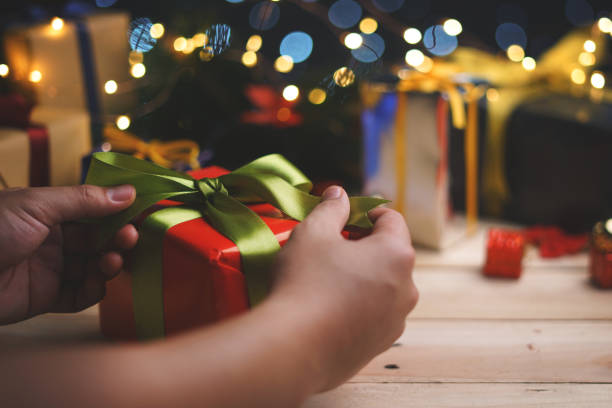 istock Hand Tying Up Red Green Christmas Present Gift 1055023834
