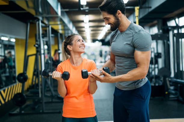 istock Personal trainer assisting beautiful woman lose weight 1055027552