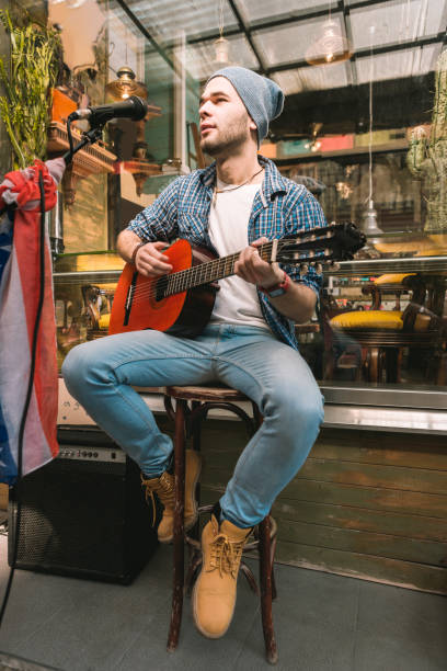 fokussierte männlichen gitarristen song vertreten in der bar - street musician stock-fotos und bilder