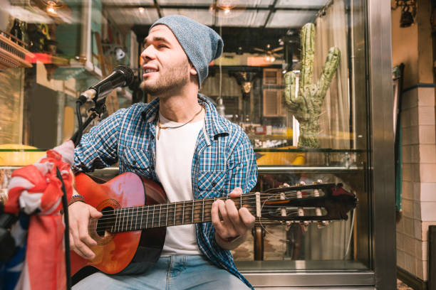 froh männlichen gitarristen reifung song in der bar - street musician stock-fotos und bilder