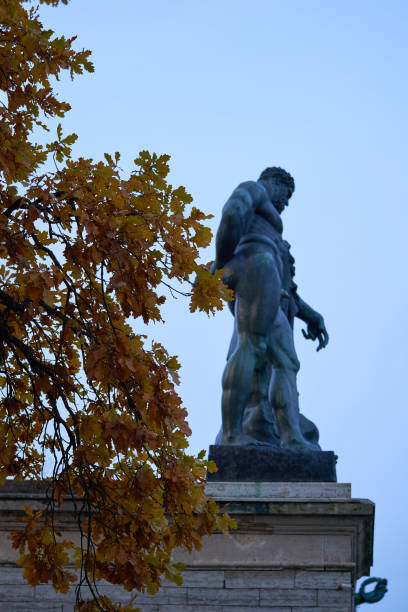 istock Ancient statue and autumn leaves on the tree in the park 1055040532