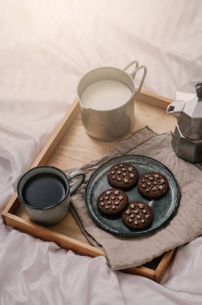 breakfast with coffee, cookies and milk served in the bed on tray, window light stock photo