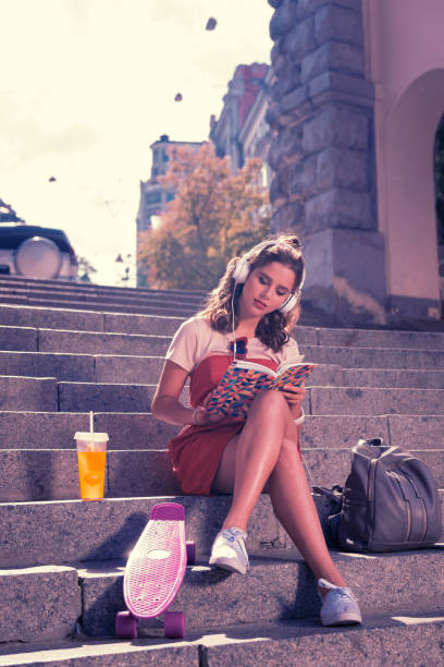 istock Young student girl sitting and reading book while waiting for her boyfriend 1055041444