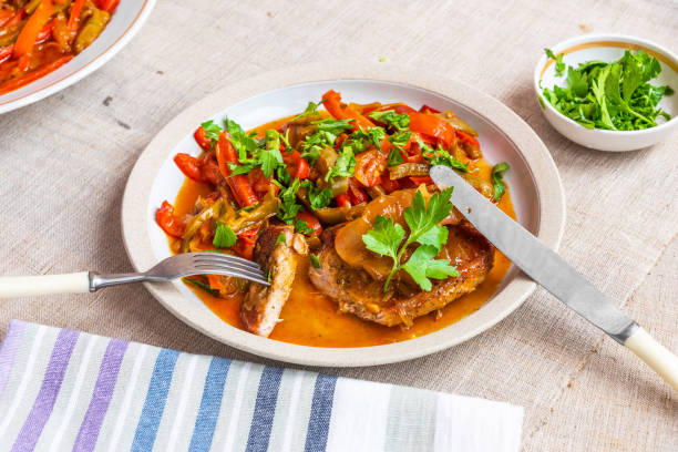istock Healthy rustic dinner - pork chop with a side dish of stewed peppers 1055043714