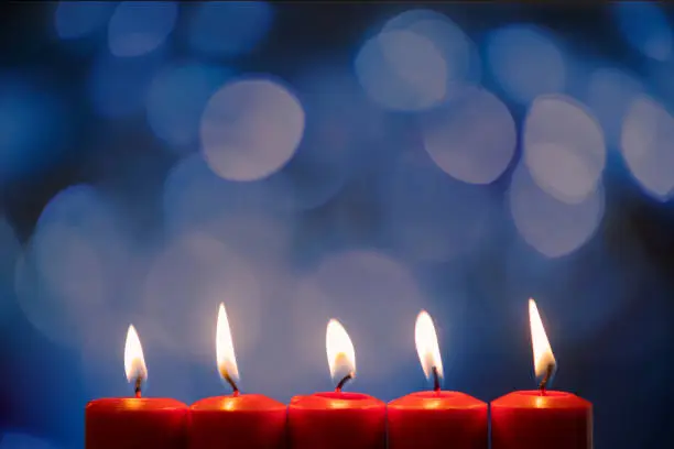 Closeup of five burning candles with blurred sparkling light background