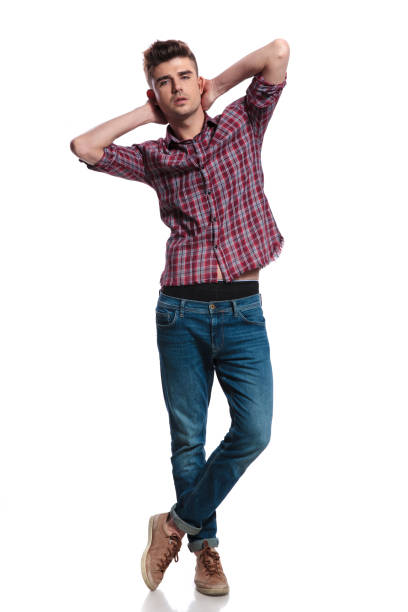 istock sensual man holds his neck while standing with legs crossed 1055052522