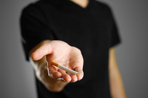 A man holding a cigarette. Close up. Isolated background.