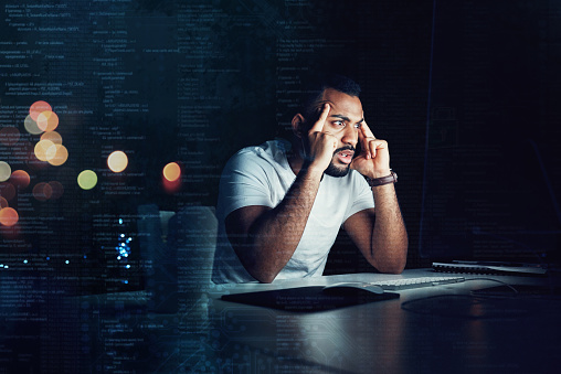 Shot of a programmer looking stressed out while working on a computer code at night