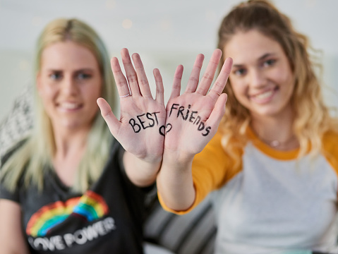 Shot of two young friends showing the palm of their hands with writing on it