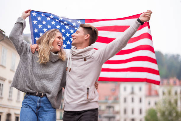 American Flag Happy young couple holding American flag while walking on the street teenager couple child blond hair stock pictures, royalty-free photos & images