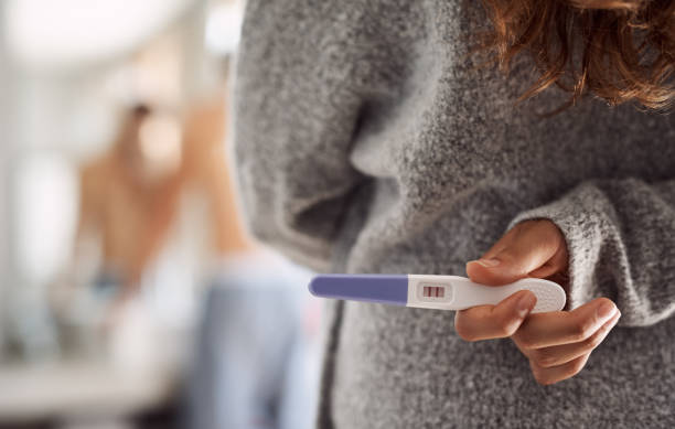 This could change everything Cropped shot of an unrecognizable woman hiding a pregnancy test behind her back in the bathroom family planning stock pictures, royalty-free photos & images