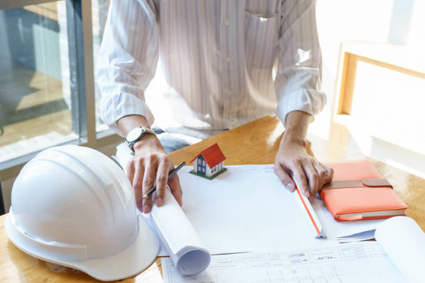 istock Architect or engineer working on blueprint at workplace on wooden desk. - architectural project, Construction concept. 1055064470
