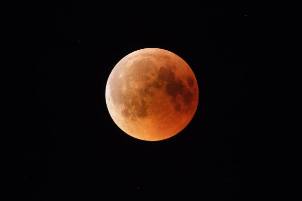 istock Super Bloody Moon, beginning of full eclipse end phase against starry sky background 1055069604
