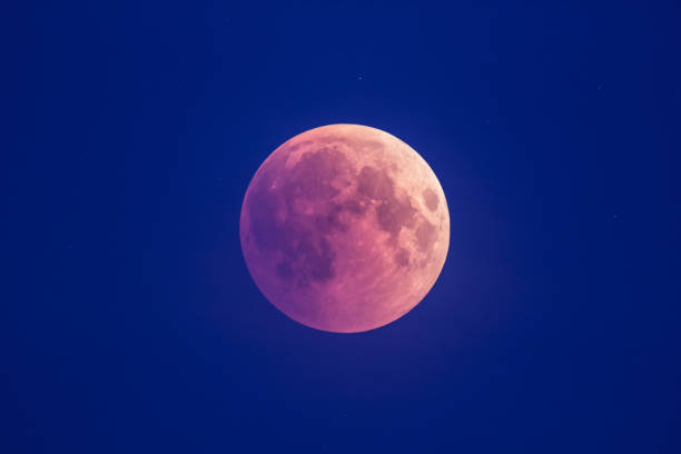 istock Super Bloody Moon, beginning of full eclipse phase against blue starry sky background 1055069992