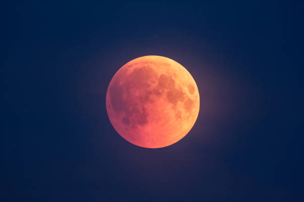 istock Super Bloody Moon, beginning of full eclipse phase against blue starry sky background 1055070042