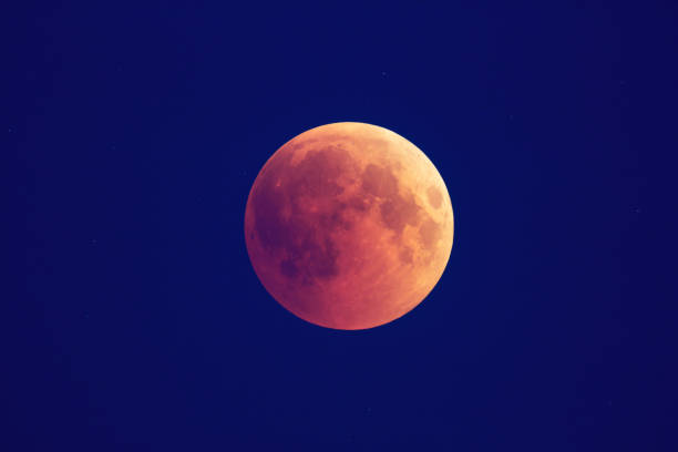 istock Super Bloody Moon, beginning of full eclipse phase against blue starry sky background 1055070076